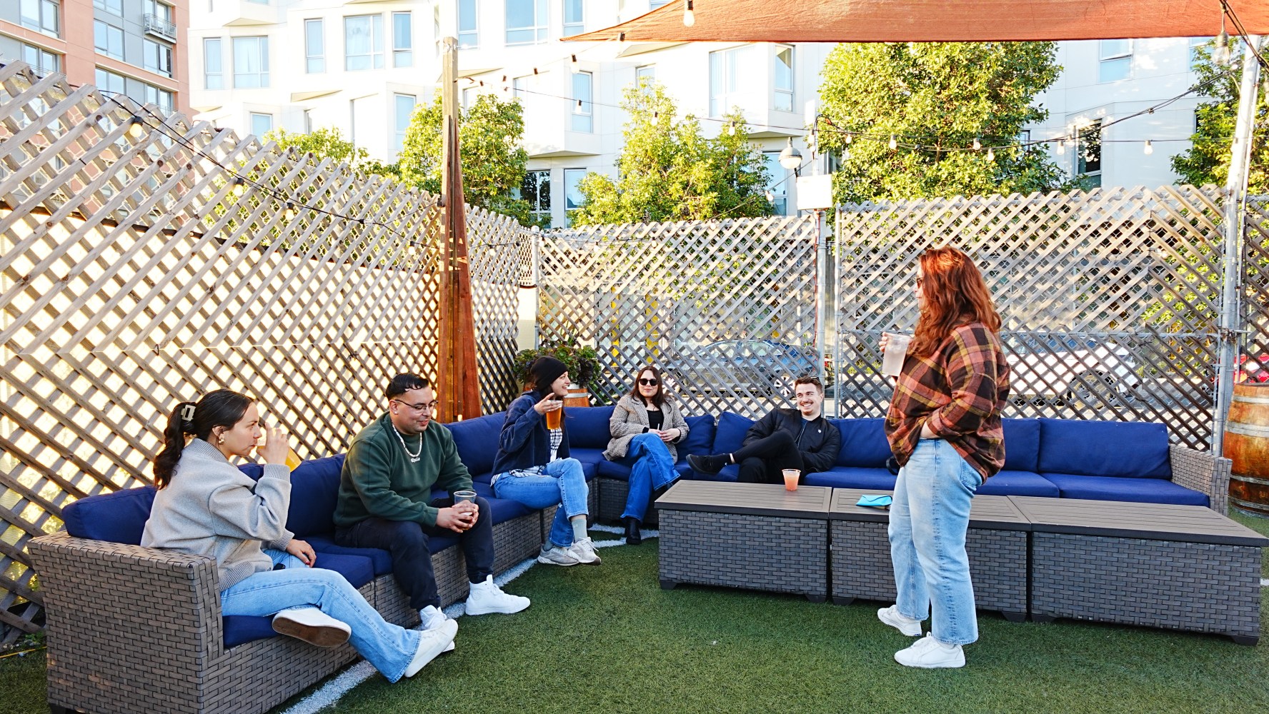 People sitting and talking on outdoor patio furniture with lattice fencing.