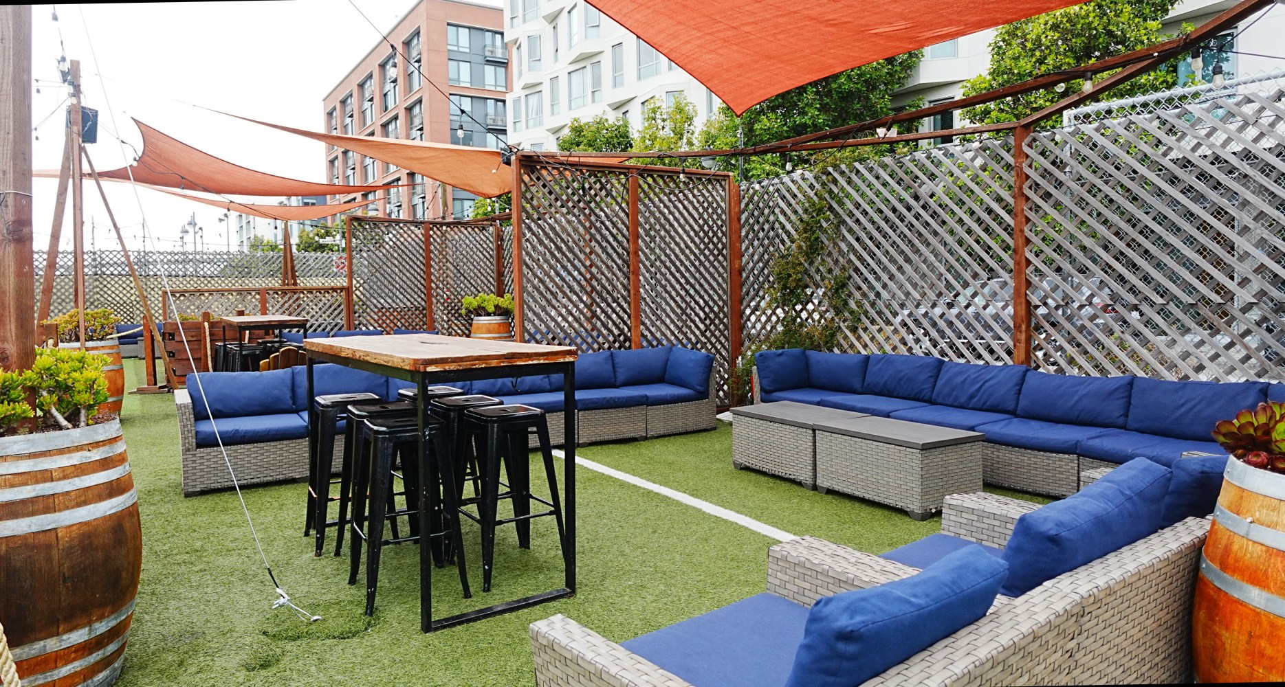 Outdoor patio with seating, tables, umbrellas, and barrel planters.