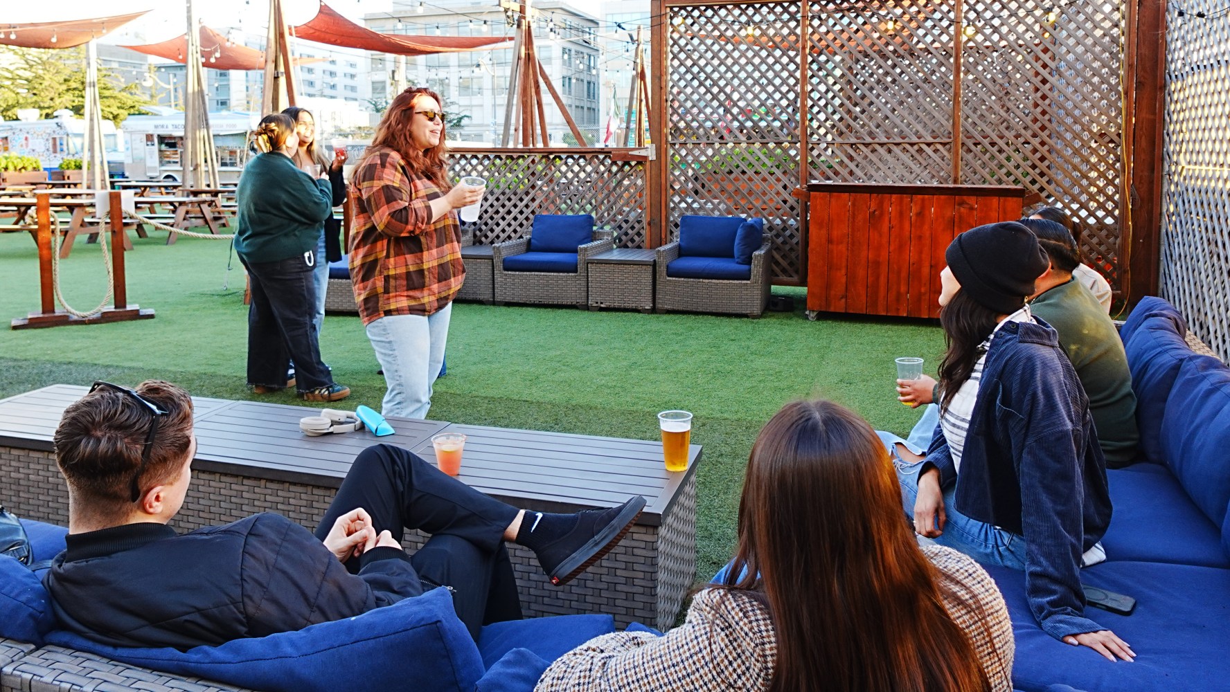 Group of friends socializing outdoors with drinks on a patio.