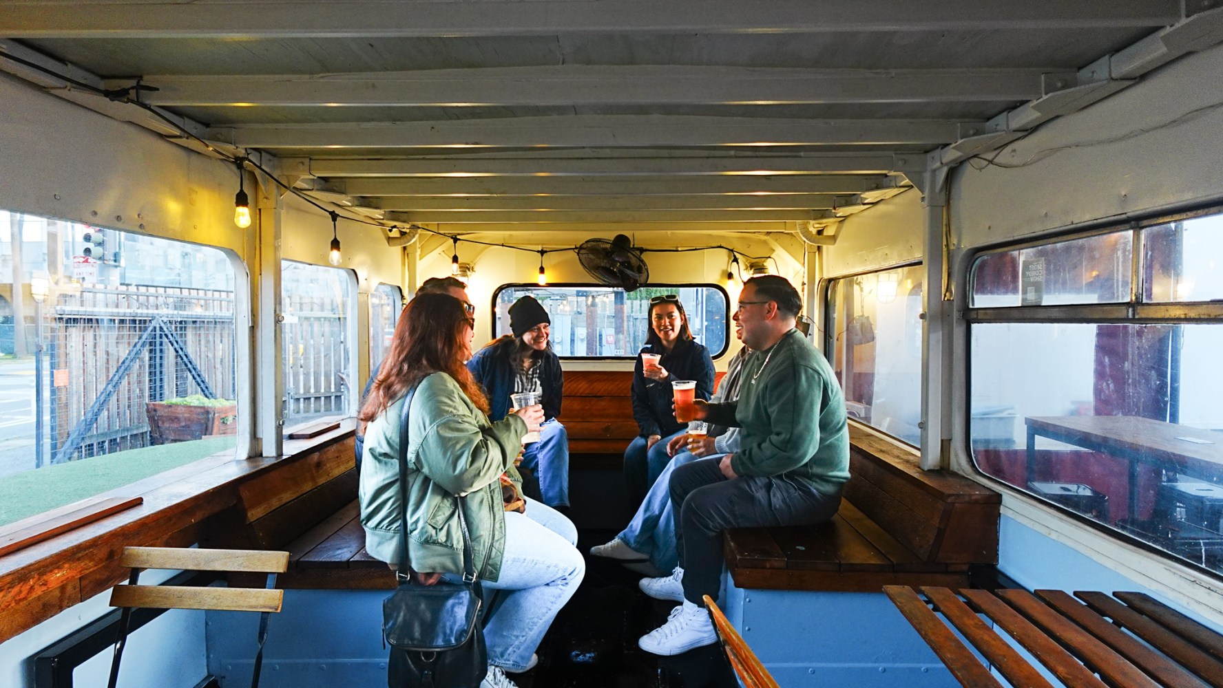 Five people seated inside a converted bus with wooden benches.