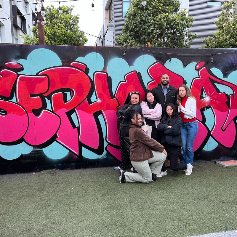 a group of people standing in front of a graffiti wall
