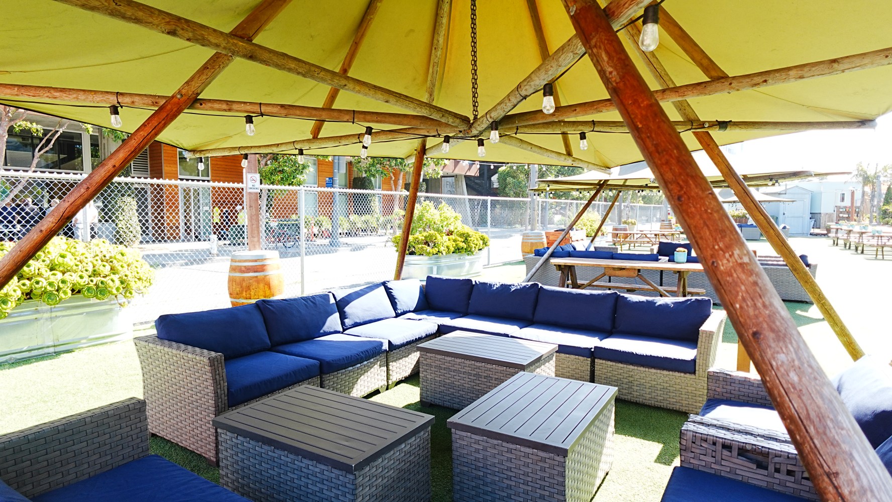 Outdoor seating area with blue cushions under a large canopy.