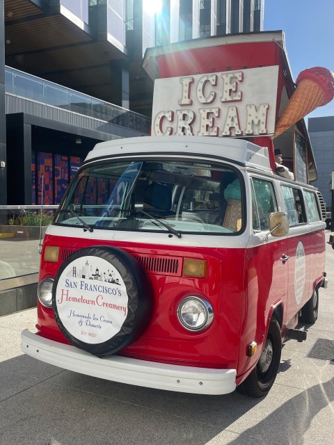 Red ice cream van with large cone on top, parked near Golden State Warriors sign.