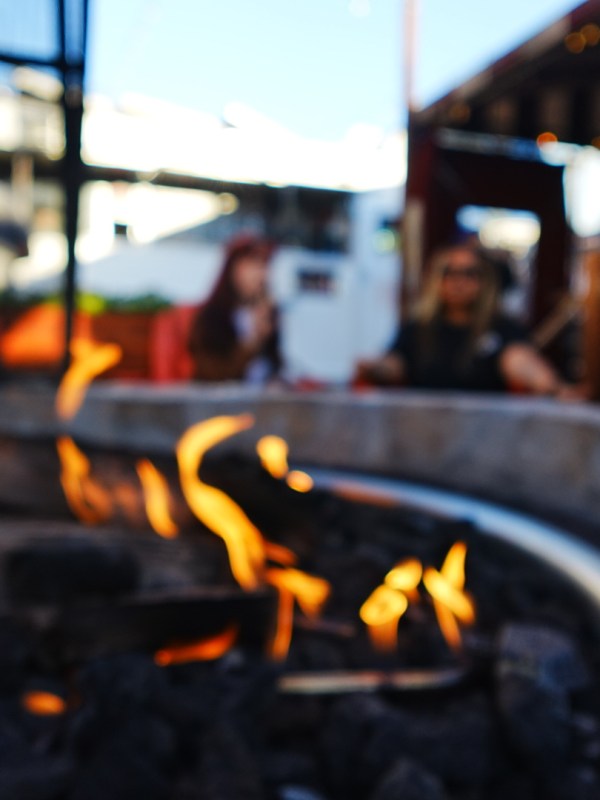 Blurry image of a fire pit with people seated around it outdoors.