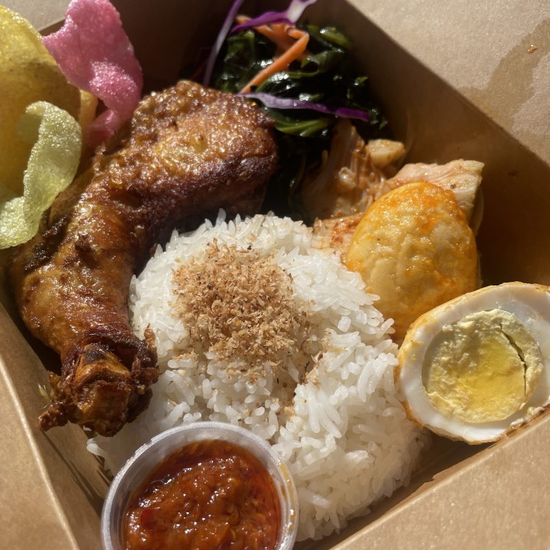 Box of rice with chicken, egg, vegetables, and sauce.