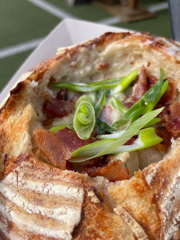 Bread bowl filled with creamy soup, bacon, and green onions.