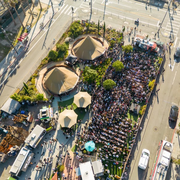 Aerial view of a crowded outdoor event with tents and food trucks on a sunny day.