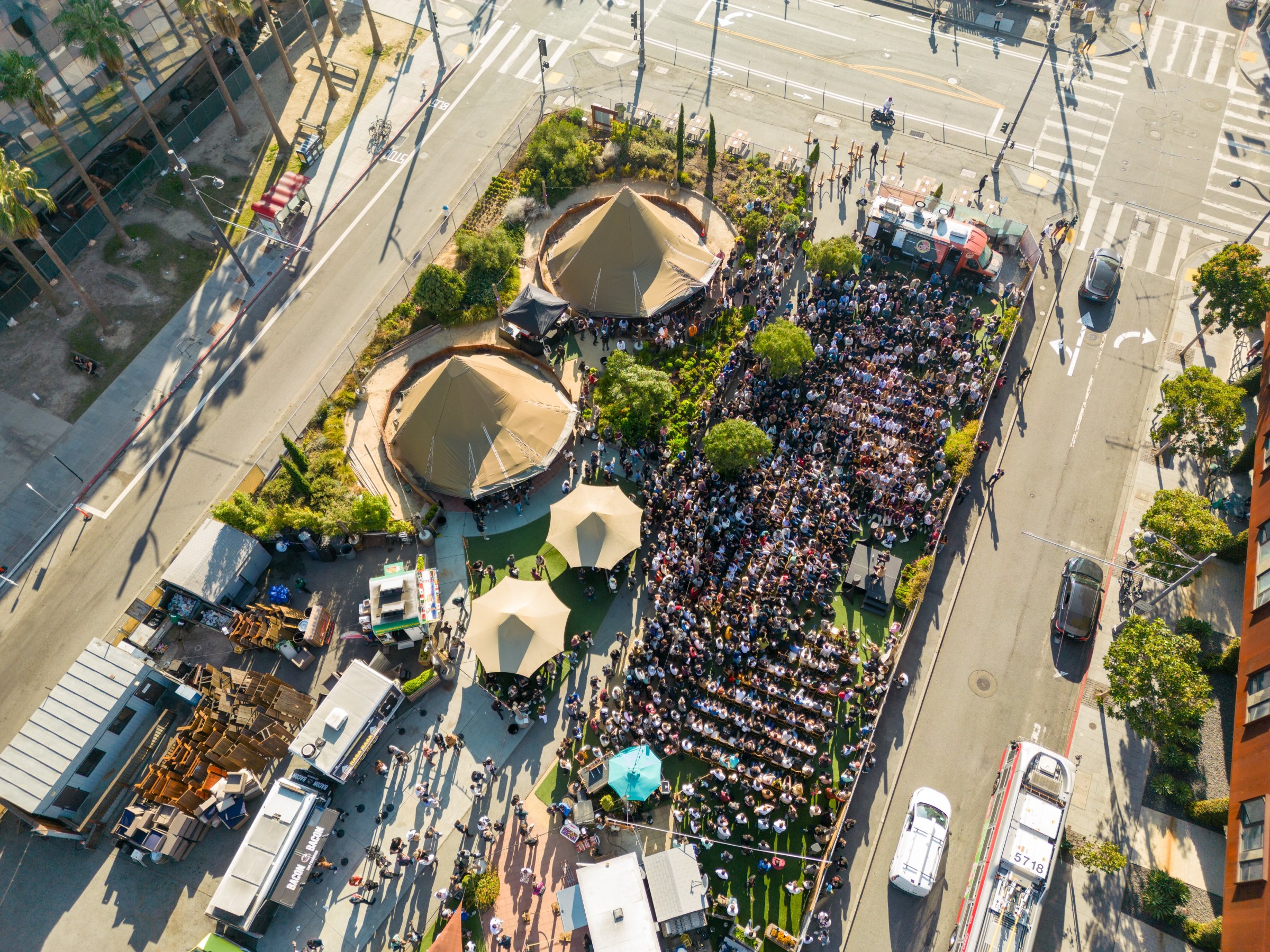 Aerial view of a large crowd at an outdoor event with tents and food trucks.