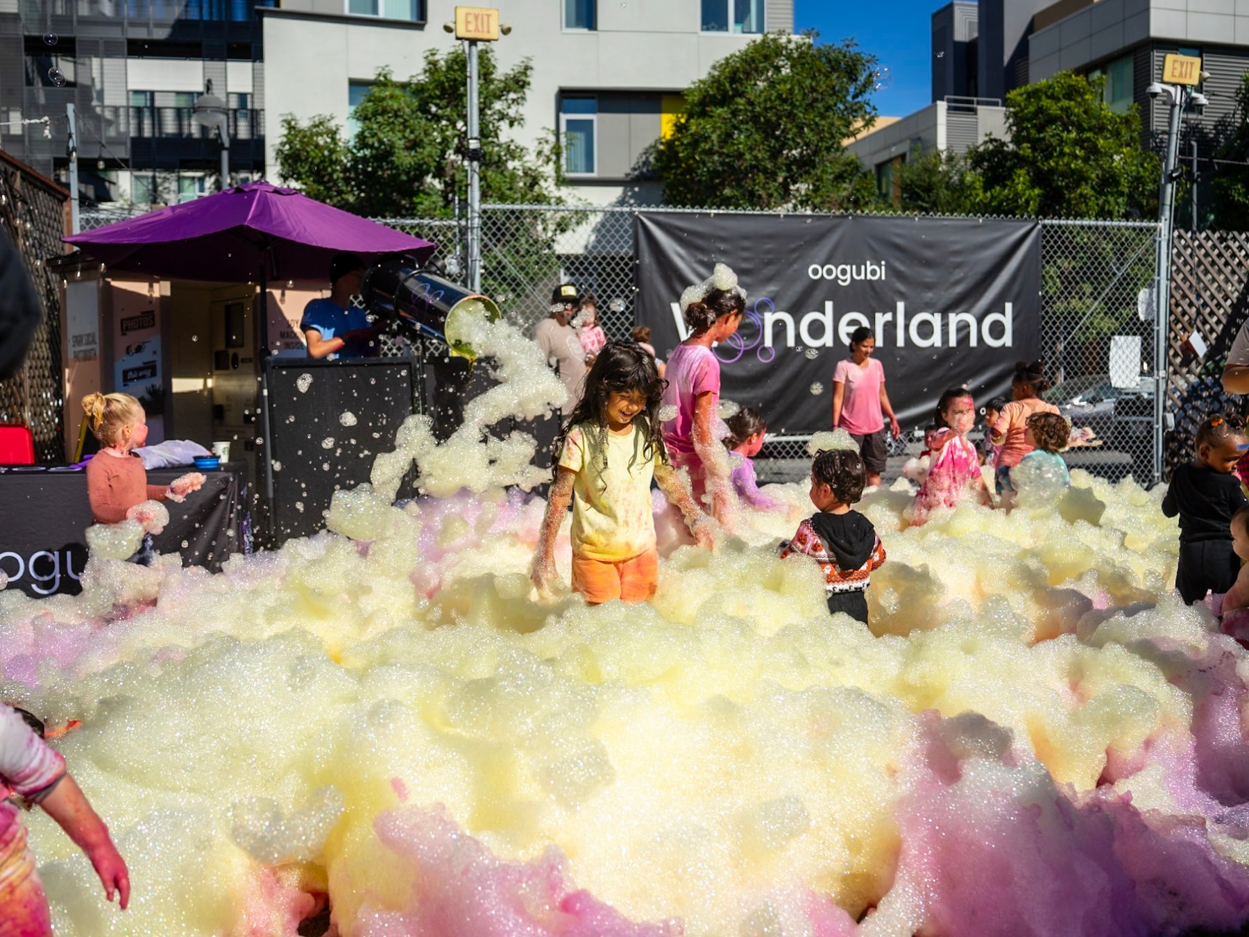 Children playing in colorful foam at an outdoor event.