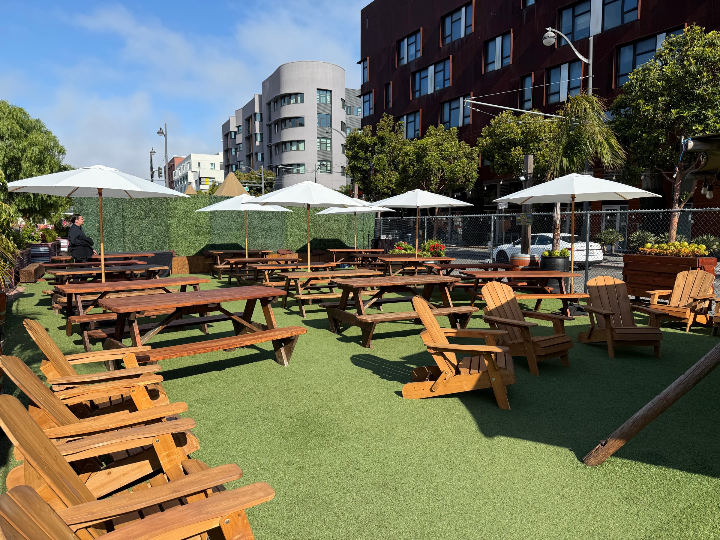 Outdoor seating area with wooden tables, chairs, and umbrellas.