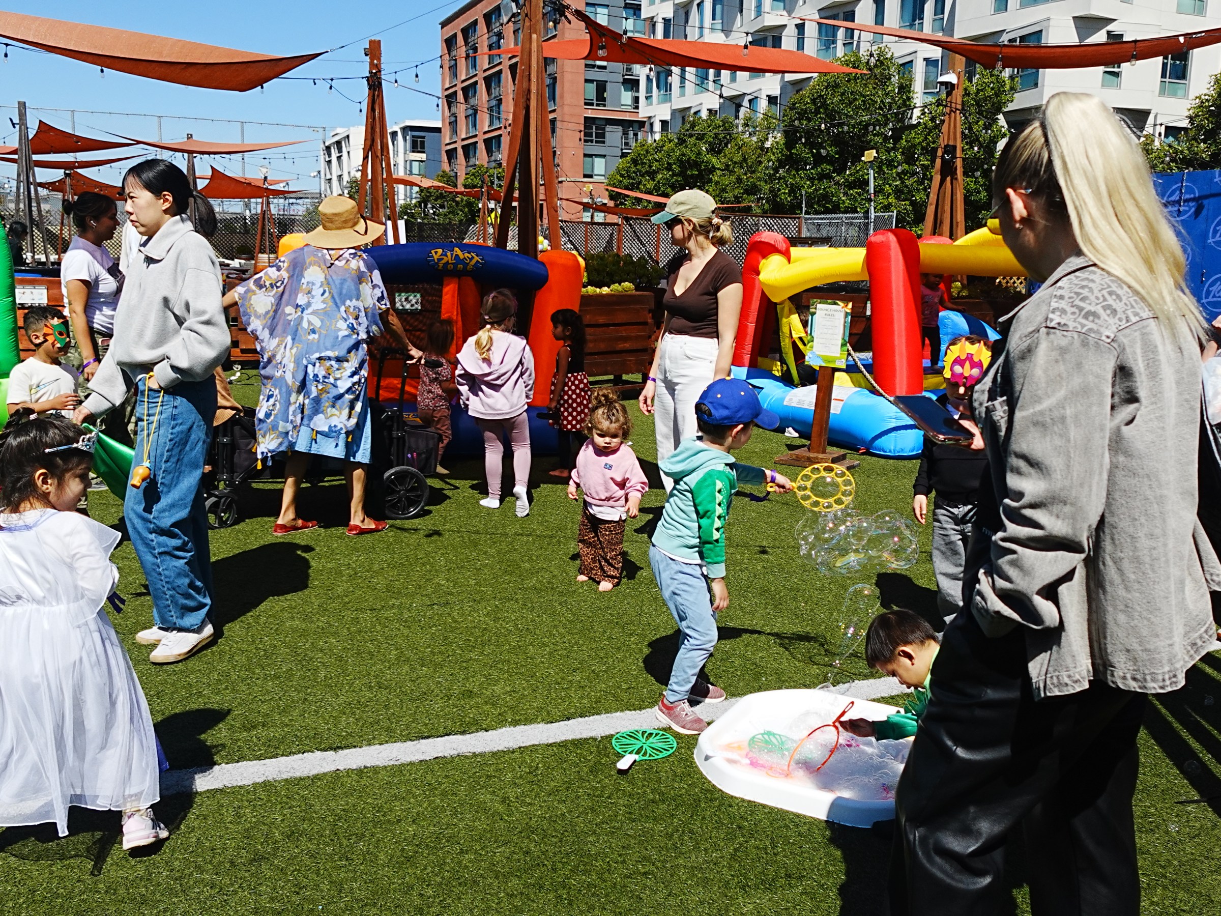 Children and adults at an outdoor event with inflatables and play equipment.